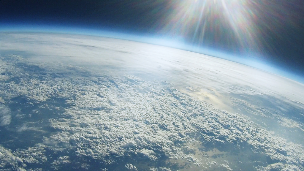 バルーンを成層圏まで打ち上げて撮影するので、成層圏から見る青い地球はホンモノ。人の顔は、あらかじめ撮影した画像を、宇宙飛行士人形にプロジェクションマッピングしたものになります