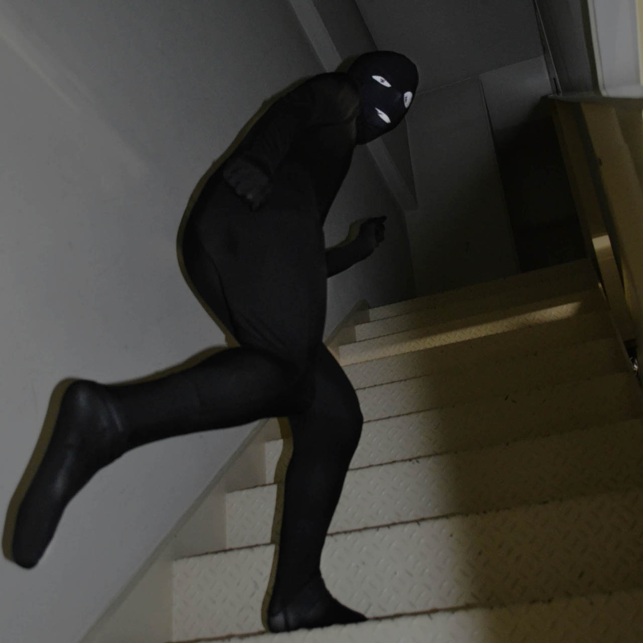 事件を起こした直後なのだろうか、ブキミな笑顔で階段を上り去っていく黒いスーツの男……