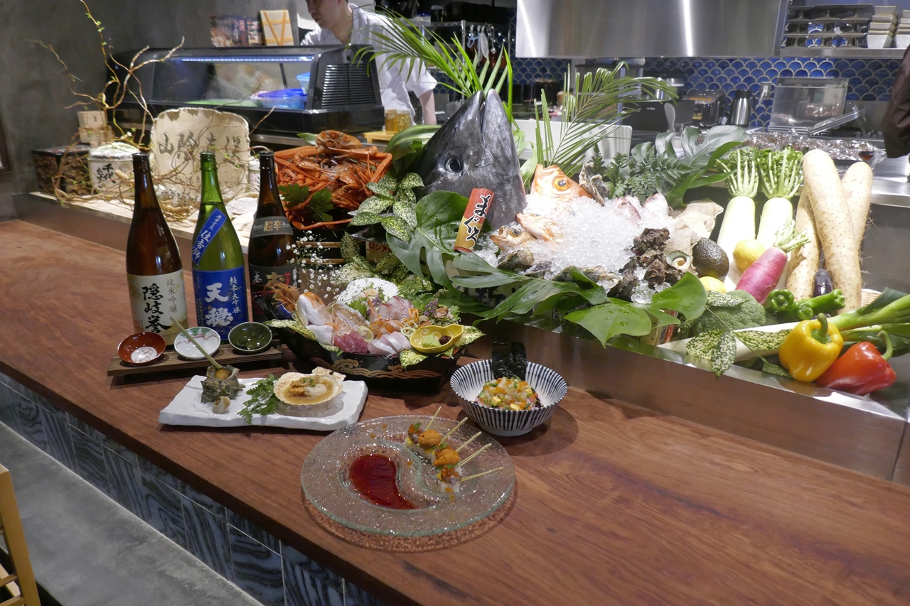 食材ディスプレイが食欲をそそる8Fの「炉端焼きと旨い酒　山陰　家富良」では、鳥取・島根など山陰地方の料理が楽しめます