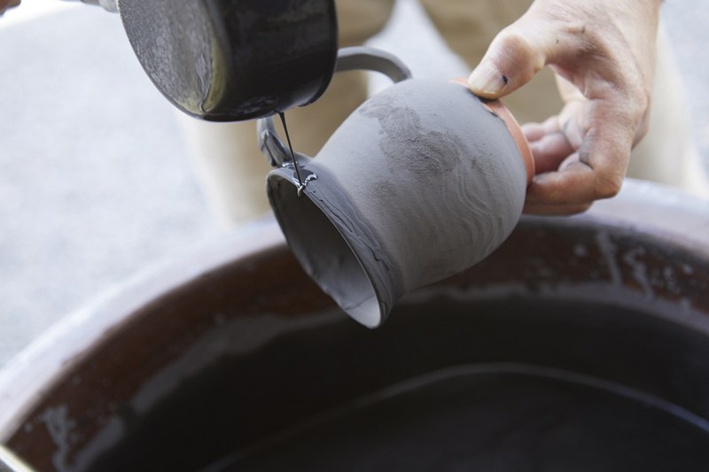 　コーヒーアロママグ小代焼は、各マグカップによって色味や持ち手の大きさが異なるところが魅力。粗めの陶土に、茶褐色の鉄釉で覆い、その上に藁や笹の灰から採った白釉や黄色釉を流し掛けする、奔放な風合いの小代焼。焼成温度などにより多彩に変化する釉薬が特徴となっています。マグ小代焼の中の釉薬は外側と違った白っぽいものにして、コーヒーの色合いが分かるように仕上げたとのこと