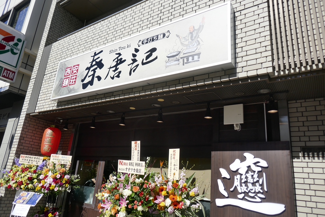 「西安麺荘　秦唐記　神保町店」。オープンまもない店頭はスタンド花で華やか
