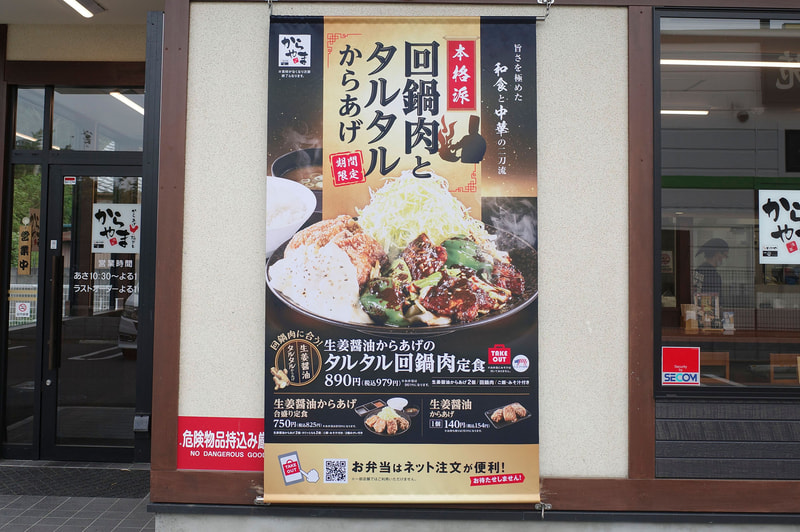 店舗入口横の壁面には巨大な「生姜醤油からあげのタルタル回鍋肉定食」、「生姜醤油からあげ合盛り定食」、「生姜醤油からあげ 1個」を紹介するポスターが貼られています！