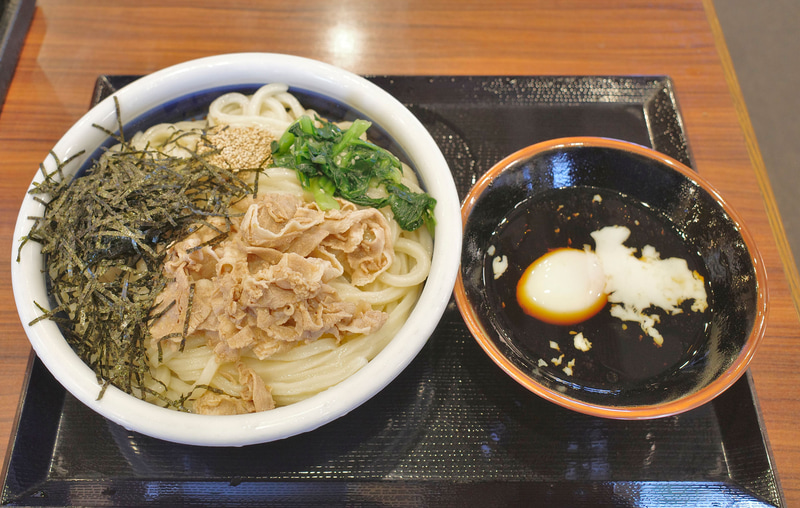 「旨辛 豚つけ汁うどん(温泉玉子付き)」は、具だくさんのうどん、温泉玉子入りのつけ汁ともどもボリューム満点！