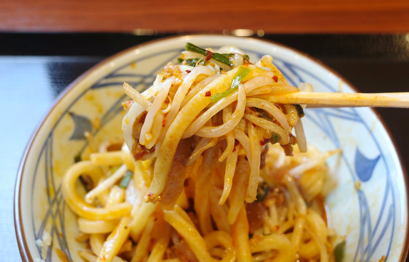 うどんに黄身、旨辛ぶっかけだし、刻んだにんにくだけではなく、豪快に具もひとまとめにしてほおばってFINISH！