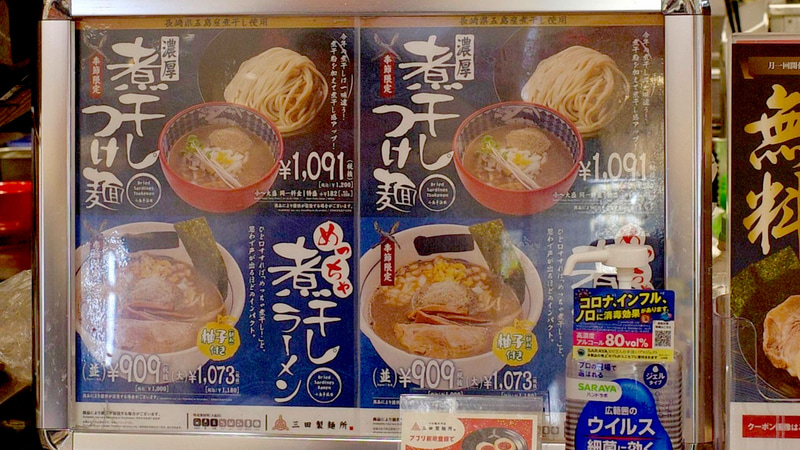 料理受け取りカウンターの脇には、額に収められたポスターで「めっちゃ煮干しラーメン」と「濃厚煮干しつけ麺」を訴求!